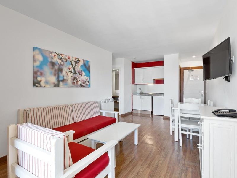 Moderní obývací pokoj s pohovkou, jídelním stolem a otevřenou kuchyní v rekreačním apartmánu.