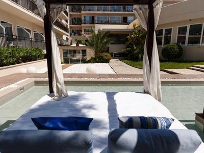 Lettino con cuscini e asciugamani accanto a una piscina in un complesso alberghiero soleggiato.