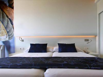 Camera moderna con letto matrimoniale, cuscini neri e design minimalista.