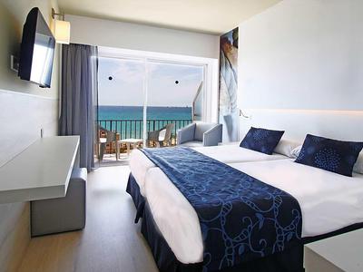 Camera d'hotel moderna con letto matrimoniale e vista mare dal balcone.