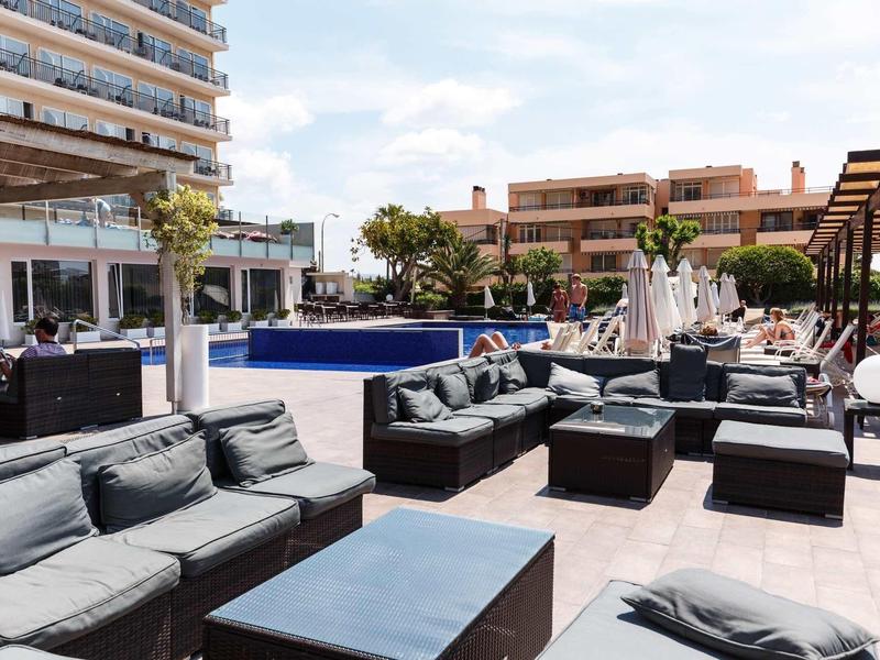 Area piscina esterna moderna con comodi posti a sedere e vista su un edificio dell'hotel.