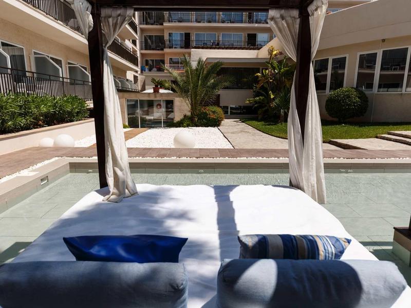 Lettino con cuscini e asciugamani accanto a una piscina in un complesso alberghiero soleggiato.