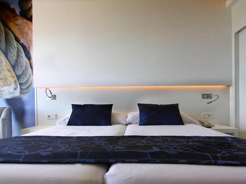 Camera moderna con letto matrimoniale, cuscini neri e design minimalista.