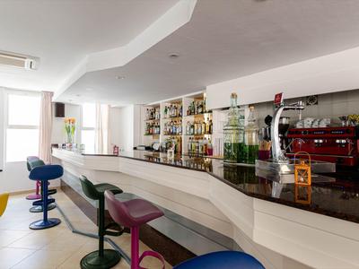 Moderne hotelbar met kleurrijke barkrukken en planken vol sterke dranken.