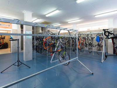 Fahrradabstellraum mit vielen Fahrrädern und Ständern auf blauem Boden.