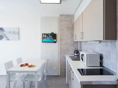 Nowoczesna kuchnia z białym stołem, mikrofalówką i obrazem na ścianie.