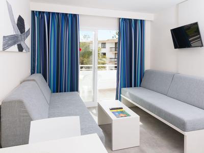 Modernes Wohnzimmer mit zwei grauen Sofas, blau gestreiften Vorhängen und einem an der Wand montierten Fernseher.