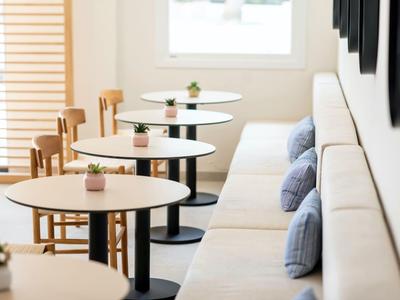 Moderne Hotel-Lounge mit runden Tischen, Holzstühlen und bequemen Polstersitzen.