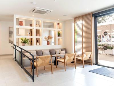 Jasny salon hotelowy z nowoczesnymi kanapami i widocznym tarasem na zewnątrz.