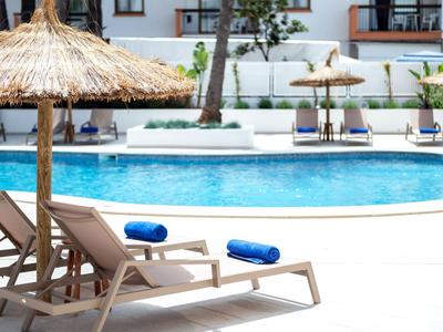 Zwei Liegestühle mit blauen Handtüchern unter Strohdächern am Pool im Hotel