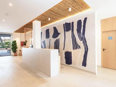 Nowoczesna recepcja hotelu z dekoracyjną ścianą i drewnianym sufitem.