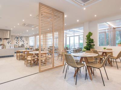 Nowoczesna jadalnia z drewnianymi stołami i krzesłami przy ażurowej ściance.