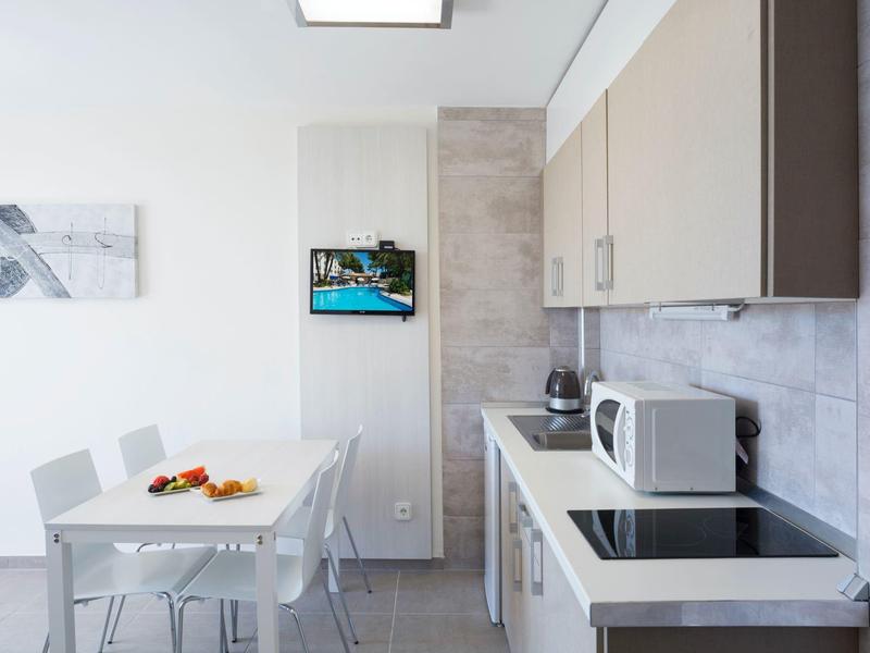 Nowoczesna kuchnia z białym stołem, mikrofalówką i obrazem na ścianie.