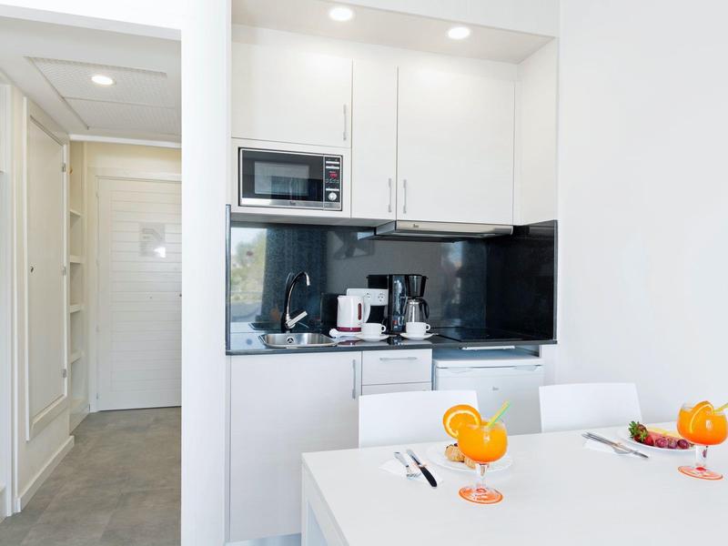 Nowoczesna kuchnia z mikrofalówką, ekspresem do kawy i białym stołem z napojami.