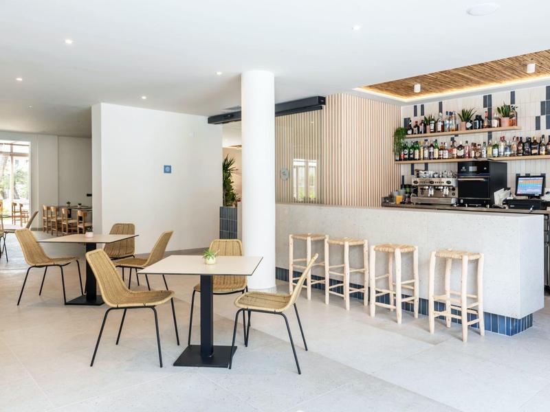 Nowoczesny bar i jadalnia z jasnymi drewnianymi krzesłami i jasnym oświetleniem.