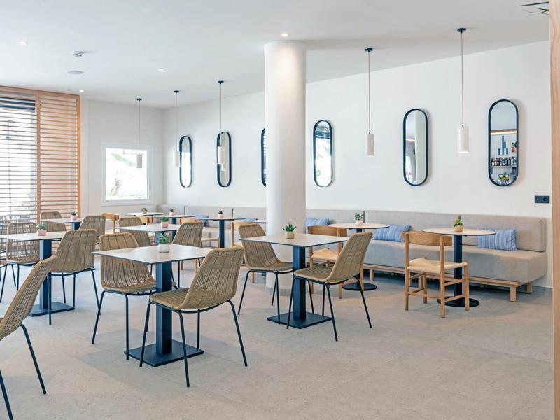 Nowoczesna jadalnia hotelowa z drewnianymi krzesłami i dużymi oknami.