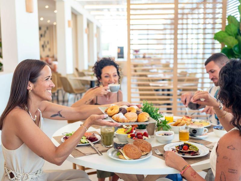 Cztery osoby jedzą razem posiłek w przytulnym i jasnym otoczeniu.