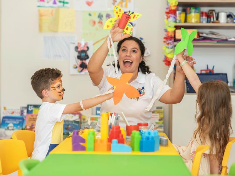 Animatorka i dzieci tworzą kolorowe gwiazdy z papieru w świetlicy.