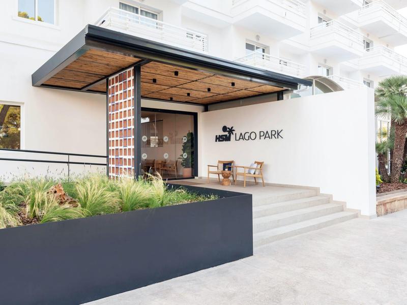 Nowoczesne wejście do hotelu z drewnianym tarasem i roślinnością.