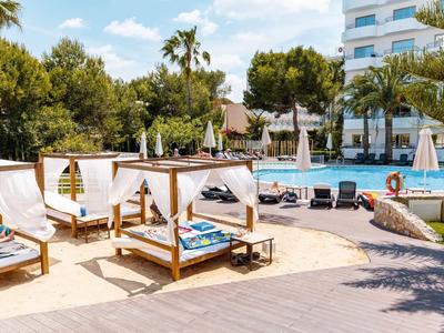 Espace piscine luxueux avec transats et lits ombragés dans un jardin d'hôtel.