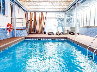 Indoor pool with blue water surface, seating area, and large windows in a hotel.