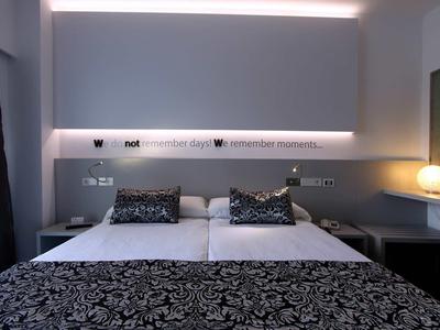 Modern hotel room with double bed, decorative pillows, and ambient indirect lighting.