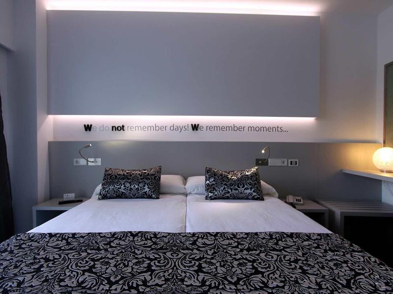 Modern hotel room with double bed, decorative pillows, and ambient indirect lighting.