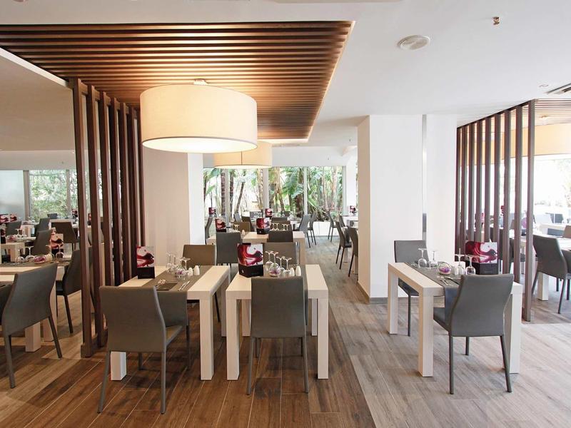 Modern hotel dining area with wooden floor and neutral-toned furniture.
