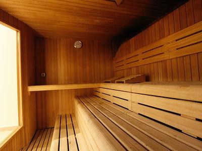 Holzsauna mit mehrstufigen Sitzbänken und großem Fenster, warme, helle Holztöne dominieren.