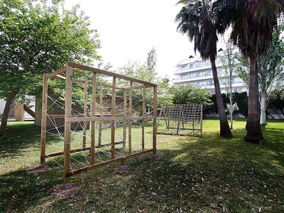 Duża pusta drewniana klatka stoi na trawie obok palm i budynku hotelu.