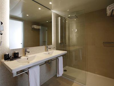 Modernes Badezimmer mit Waschbecken, Spiegel und Glasdusche in neutralen Farben