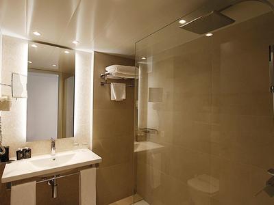 Modernes Badezimmer mit Dusche, Waschbecken und beleuchtetem Spiegel.