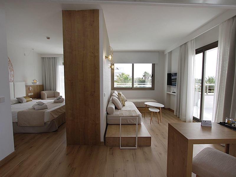 Moderner Hotelraum mit Sitzbereich, Doppelbett und großem Fenster mit Blick nach draußen.