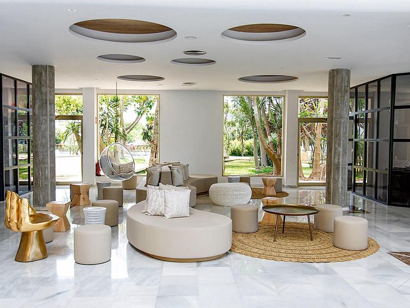 Modern eingerichteter Hotel-Loungebereich mit hellen Möbeln und großem Fensterblick auf Garten