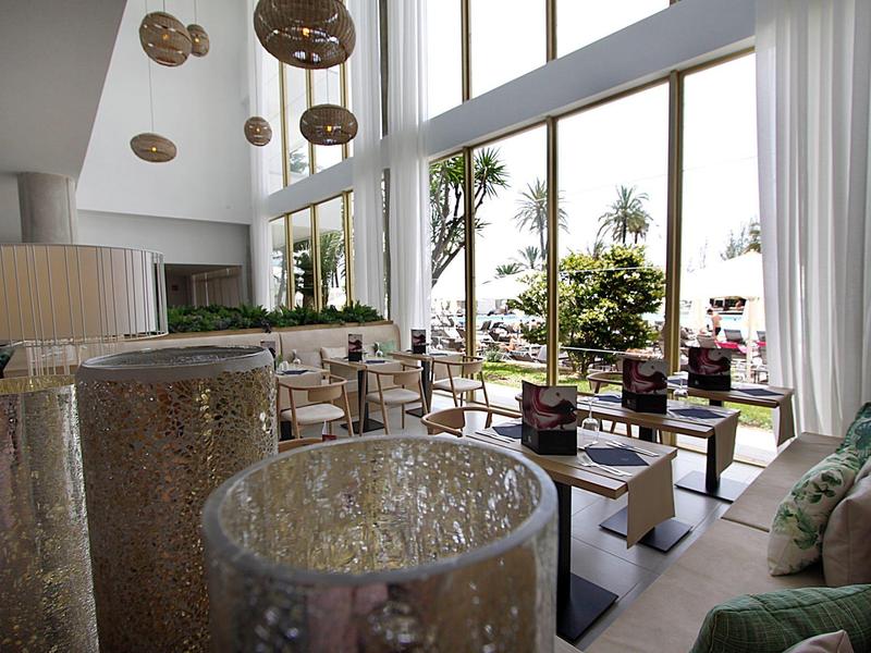 Modern eingerichteter Hotel-Loungebereich mit großen Fenstern und Blick auf Außenpflanzen.