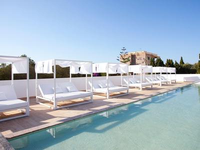 Luxe zwembadgedeelte met witte ligstoelen en baldakijnen onder een blauwe hemel.