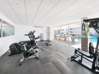 Salle de sport moderne avec équipements d'entraînement et vue sur la piscine de l'hôtel.