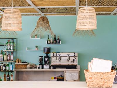 Barbereich mit Kaffeemaschine, Getränkeflaschen und dekorativen Lampen in einem Café