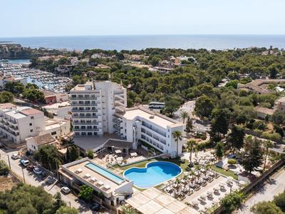 Blick auf ein Hotel mit Pool und Liegestühlen nahe der Küste und umgeben von Grünflächen.