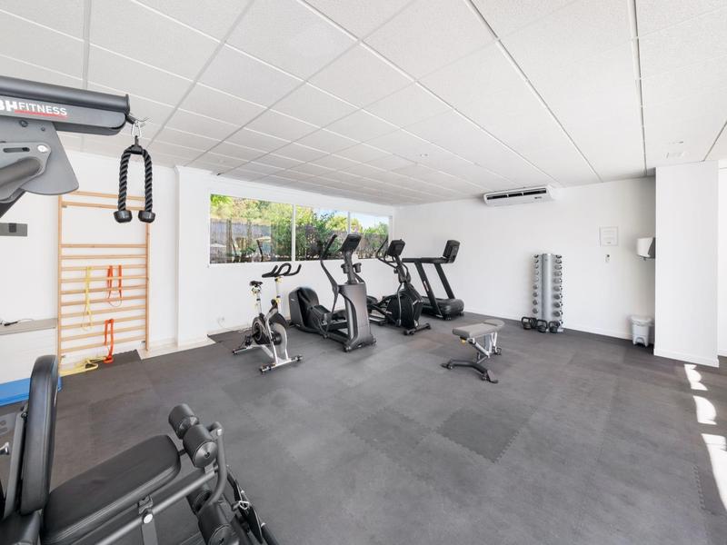 Moderner Fitnessraum in einem Hotel mit verschiedenen Trainingsgeräten und viel Tageslicht.