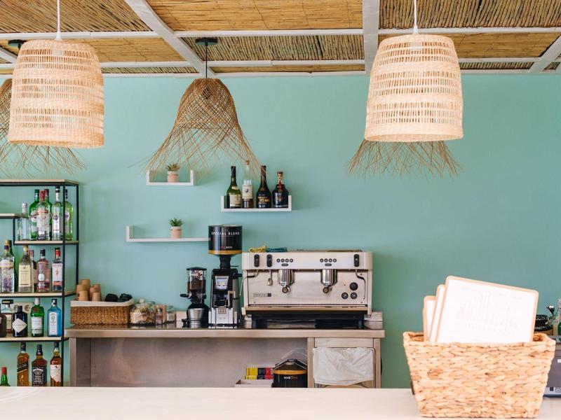 Barbereich mit Kaffeemaschine, Getränkeflaschen und dekorativen Lampen in einem Café