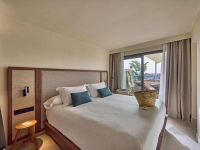 Modernes Schlafzimmer mit großem Bett, hellen Wänden, Holzlampe und Balkon mit Blick.