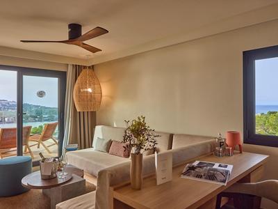 Helles Wohnzimmer mit Sofa, Holztisch, Deckenventilator und Terrasse mit Meerblick.