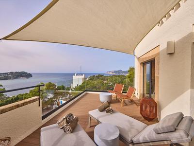Terrassenbereich mit gemütlichen Sitzmöbeln, Sonnensegel und Blick auf Meer und Inseln.