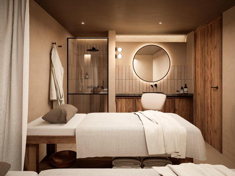 Gemütlicher Massageraum mit Behandlungsbank, rundem Spiegel, warmen Holzakzenten und sanfter Beleuchtung.