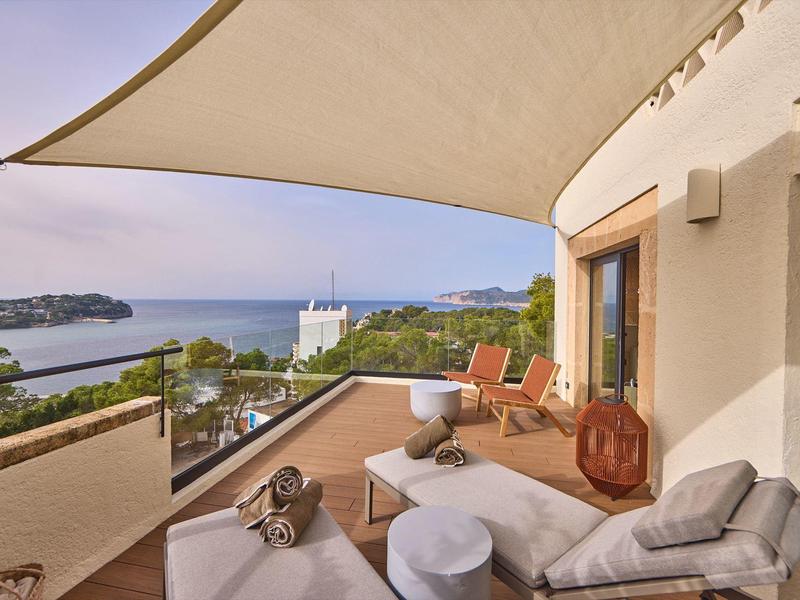Terrassenbereich mit gemütlichen Sitzmöbeln, Sonnensegel und Blick auf Meer und Inseln.