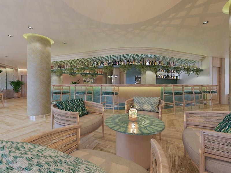 Moderna zona de salón de hotel con cómodos sillones de ratán y una gran barra al fondo.