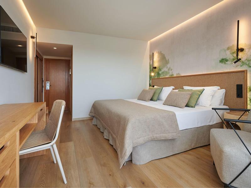 Habitación de hotel moderna con cama doble, escritorio y iluminación indirecta.