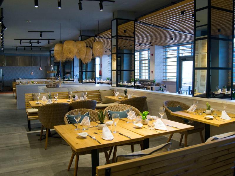 Restaurante moderno con mesas de madera, bancas cómodas y luz cálida