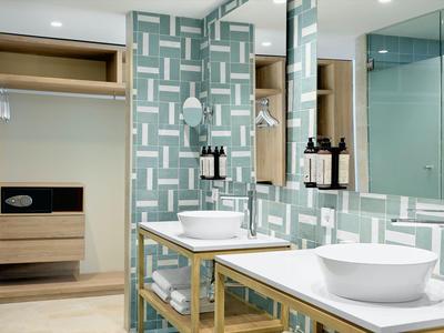 Moderne badkamer met witte wastafels, spiegels en een kluis in een hotelomgeving.